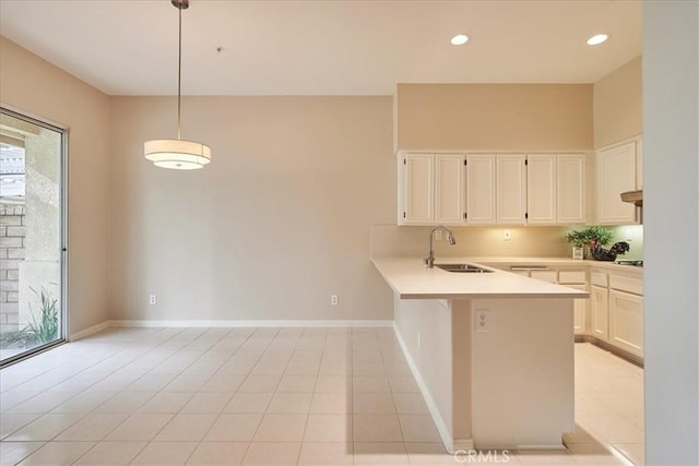 kitchen featuring decorative light fixtures, kitchen peninsula, sink, white cabinetry, and light tile patterned floors