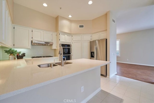 kitchen with appliances with stainless steel finishes, white cabinetry, sink, kitchen peninsula, and light tile patterned floors