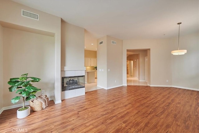 unfurnished living room featuring a multi sided fireplace and light wood-type flooring