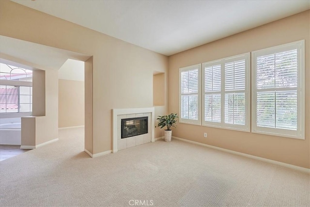 unfurnished living room featuring light carpet and a tiled fireplace