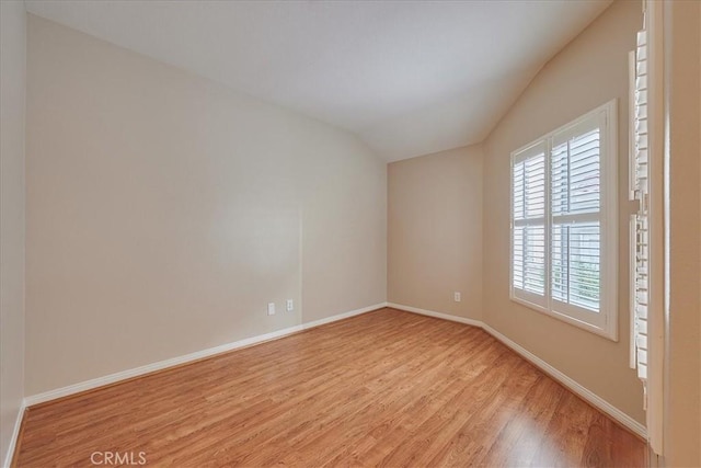 empty room with light wood-type flooring and vaulted ceiling