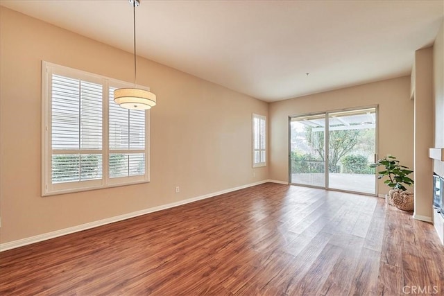 spare room with baseboards and wood finished floors