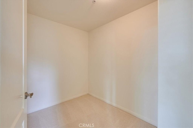 spare room with light carpet and baseboards