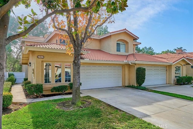 mediterranean / spanish home featuring a tiled roof, an attached garage, driveway, and stucco siding