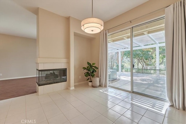 unfurnished living room with baseboards, a tile fireplace, and tile patterned floors