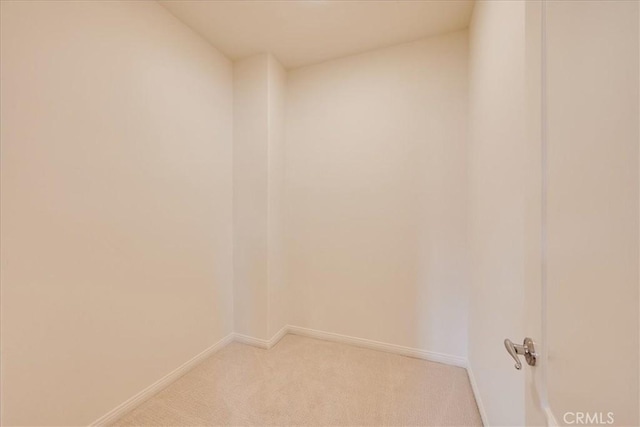 spare room with baseboards and light colored carpet