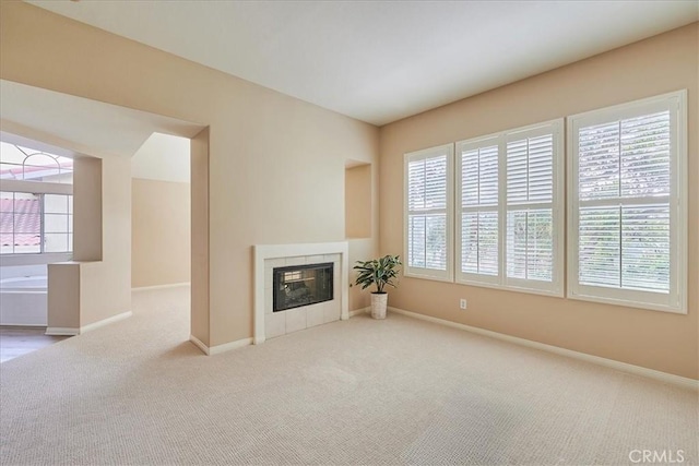 unfurnished living room featuring a healthy amount of sunlight, carpet, baseboards, and a tile fireplace