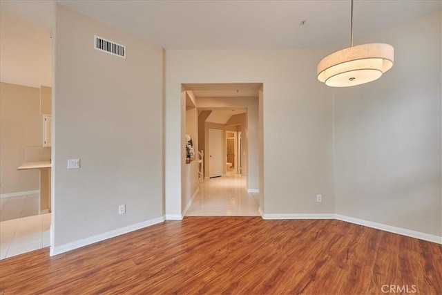 unfurnished room with baseboards, visible vents, and wood finished floors