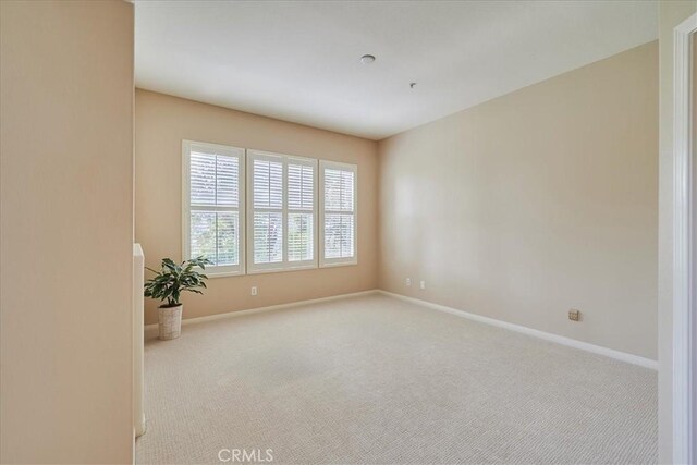 spare room featuring carpet flooring and baseboards