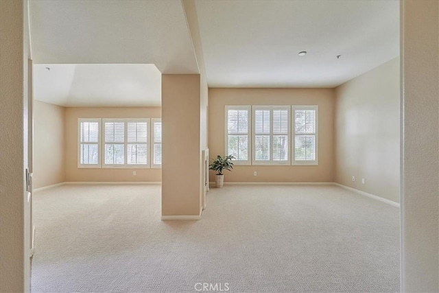 carpeted empty room featuring baseboards and a wealth of natural light