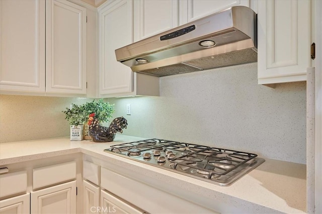 kitchen featuring stainless steel gas stovetop, light countertops, white cabinets, and under cabinet range hood