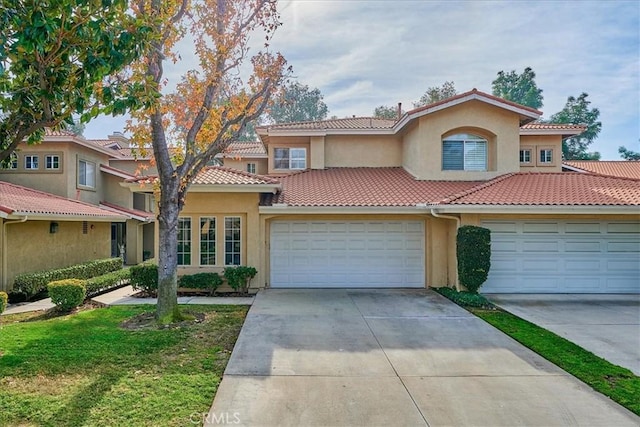 view of front of home featuring a tile roof, stucco siding, an attached garage, driveway, and a front lawn