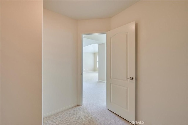 corridor featuring light colored carpet and baseboards