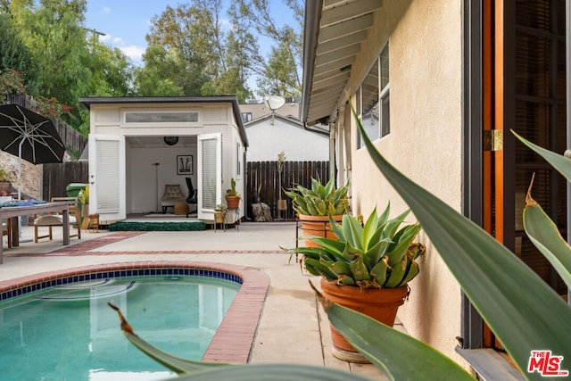 view of swimming pool with an outbuilding and a patio area