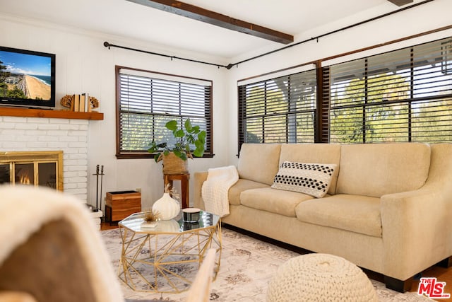 living room with a brick fireplace, crown molding, beam ceiling, and light hardwood / wood-style floors