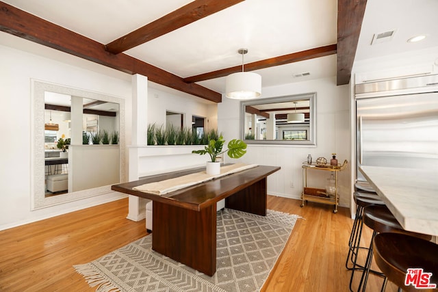 dining room featuring beam ceiling and light hardwood / wood-style floors