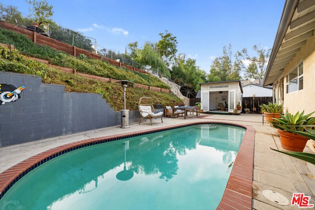 view of swimming pool featuring a patio area and an outbuilding