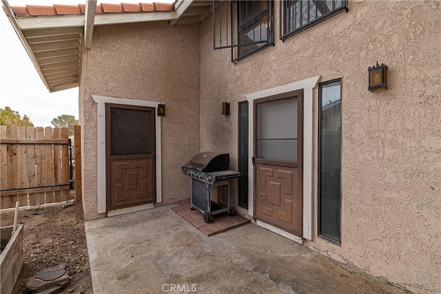 doorway to property featuring a patio, fence, and stucco siding