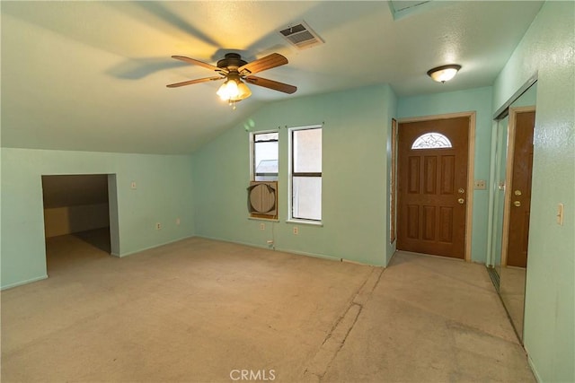 foyer featuring light carpet, visible vents, vaulted ceiling, and a ceiling fan