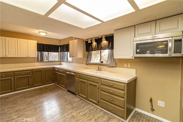 kitchen featuring dark wood-type flooring, sink, white cabinetry, appliances with stainless steel finishes, and tile counters