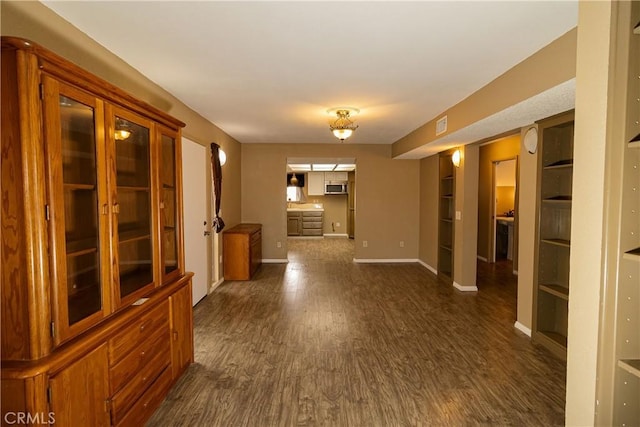 hallway featuring dark wood-style flooring, visible vents, and baseboards