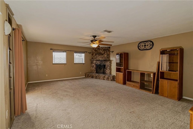 unfurnished living room featuring ceiling fan, carpet flooring, and a stone fireplace