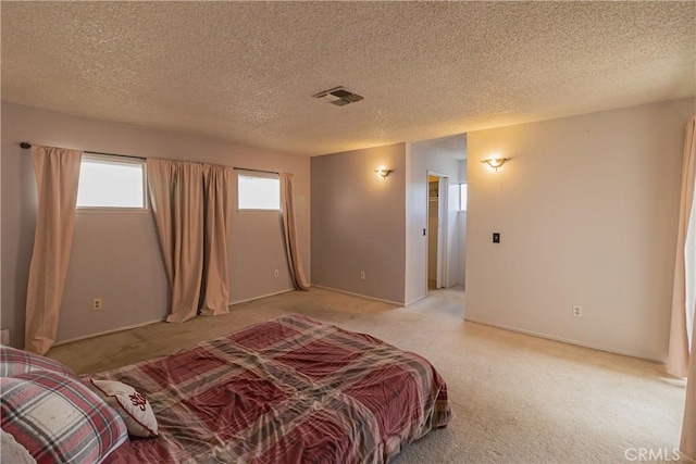 bedroom with visible vents, light carpet, and a textured ceiling