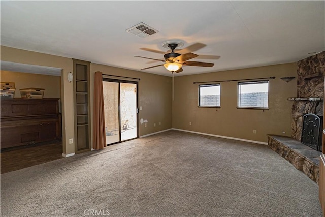 unfurnished living room featuring ceiling fan, a fireplace, carpet flooring, visible vents, and baseboards