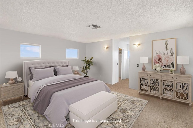 bedroom featuring carpet, visible vents, and a textured ceiling