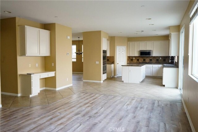 kitchen with light tile patterned flooring, a center island, stainless steel appliances, and tasteful backsplash