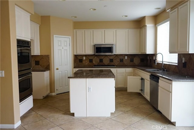 kitchen with white cabinets, appliances with stainless steel finishes, sink, and a center island