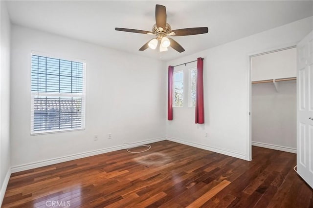 unfurnished bedroom featuring ceiling fan, dark hardwood / wood-style flooring, a closet, and a spacious closet