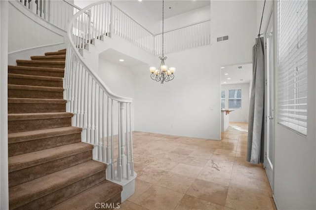 staircase with a high ceiling and a notable chandelier