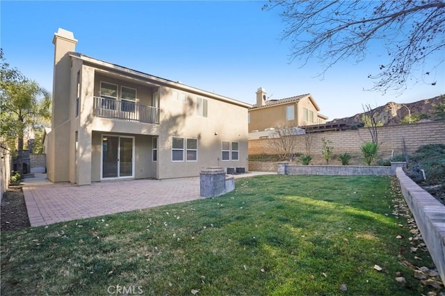 rear view of house with a balcony, a yard, and a patio area