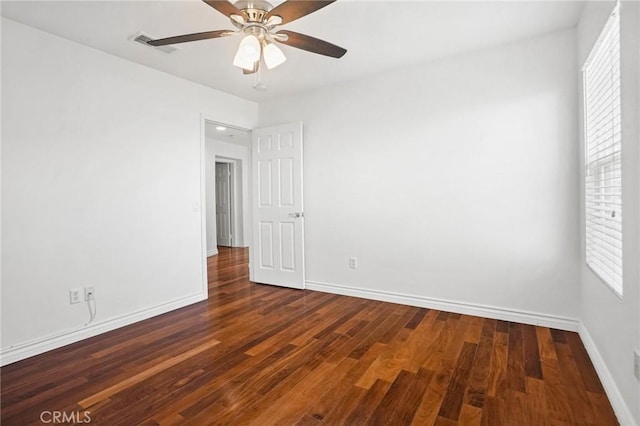 spare room with dark wood-type flooring, ceiling fan, and a wealth of natural light