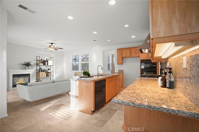 kitchen with sink, a kitchen island with sink, range hood, black dishwasher, and light stone countertops