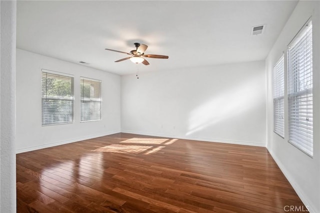 unfurnished room featuring a wealth of natural light, dark hardwood / wood-style floors, and ceiling fan