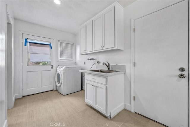 clothes washing area with cabinets, washer and dryer, and sink