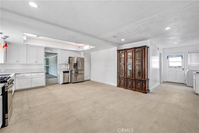 kitchen featuring white cabinets, stainless steel appliances, and a tray ceiling