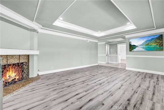 unfurnished living room with a tray ceiling, light hardwood / wood-style flooring, and ornamental molding