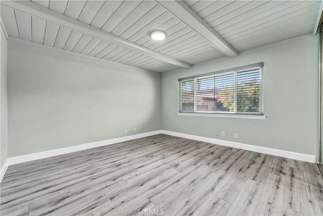 empty room with beamed ceiling, wood ceiling, and light hardwood / wood-style flooring