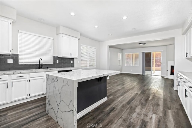 kitchen with a kitchen island, white cabinetry, tasteful backsplash, and light stone countertops