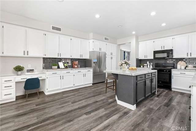 kitchen with white cabinets, black appliances, a kitchen island, dark hardwood / wood-style floors, and a breakfast bar