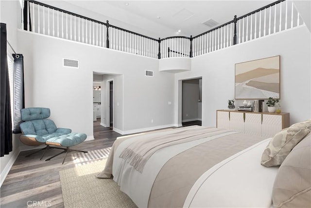 bedroom with a towering ceiling and hardwood / wood-style floors