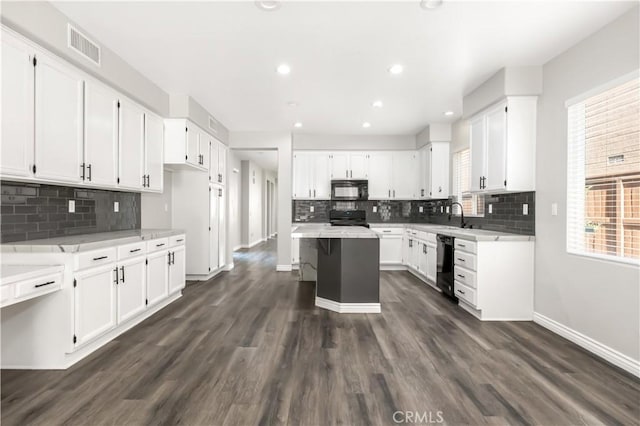 kitchen featuring dark wood-type flooring, a kitchen island, black appliances, white cabinets, and sink