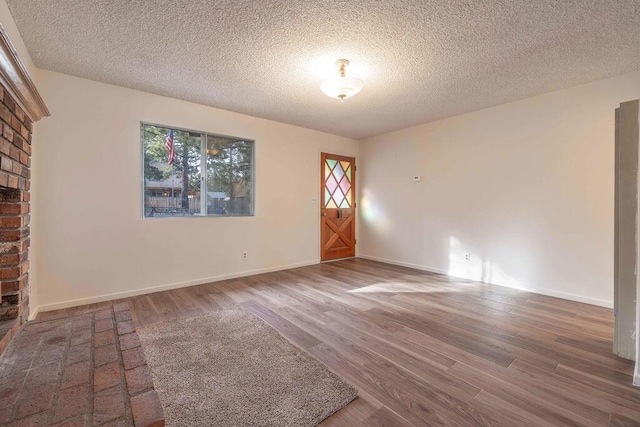 unfurnished living room with hardwood / wood-style flooring and a textured ceiling