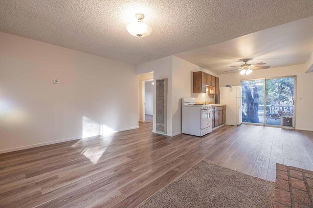 kitchen with ceiling fan, white appliances, a textured ceiling, and hardwood / wood-style floors