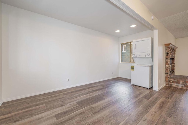 unfurnished living room with stacked washer / dryer, wood-type flooring, and a textured ceiling