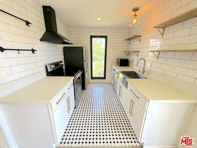 kitchen with sink, wall chimney range hood, white cabinets, and appliances with stainless steel finishes