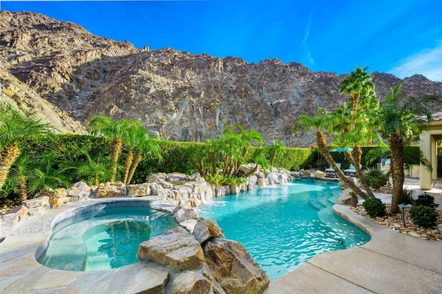 view of swimming pool with pool water feature, a mountain view, and an in ground hot tub